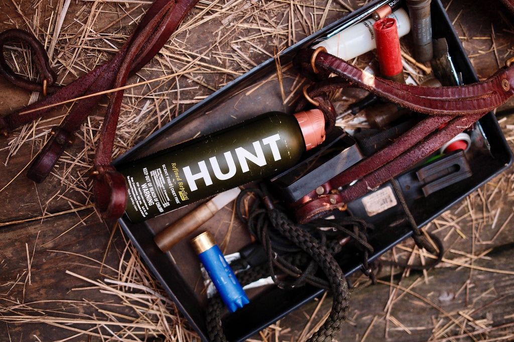 A photo of HUNT Refined Repellent Spray among other hunting equipment.
