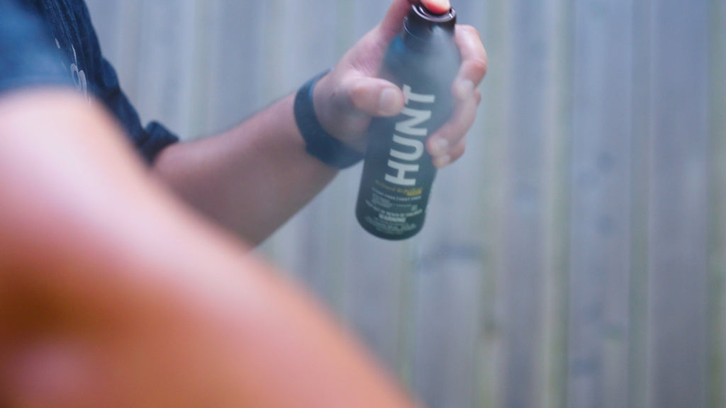 A photo of someone applying HUNT Refined Repellent Spray.