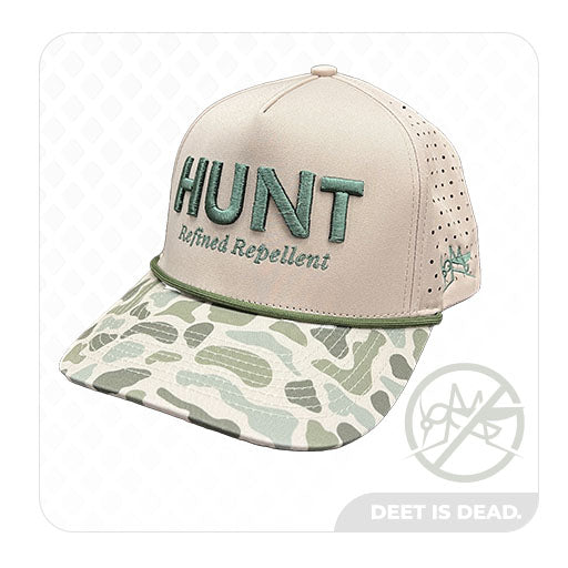 Product photo of the HUNT Refined Repellent Adjustable Camo Rope Cap. The cap is beige with camo brim and green rope around it. The cap features the logo for HUNT Refined Repellent and a mosquito on the sides of the hat.