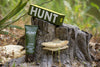 An image of a bottle of HUNT Repellent and its product box on a tree stump.