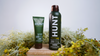 HUNT Refined Repellent Lotion and Spray on a wooden block with foliage in the background.