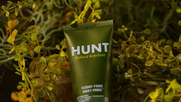 Tube of Hunt Refined Repellent Lotion surrounded by green foliage