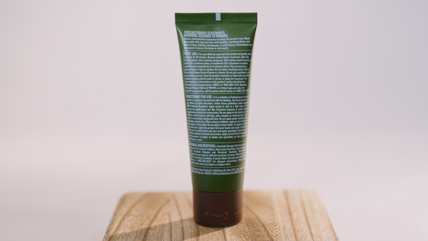 Green tube of Hunt Refined Repellent Lotion on a wooden block with a white background. It is facing backwards to show to information on the back of the bottle.