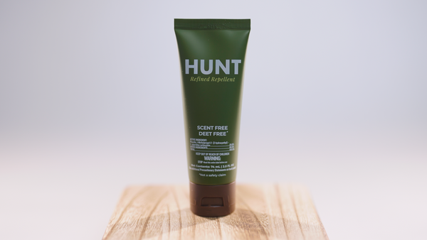 Green tube of Hunt Refined Repellent Lotion on a wooden block with a white background