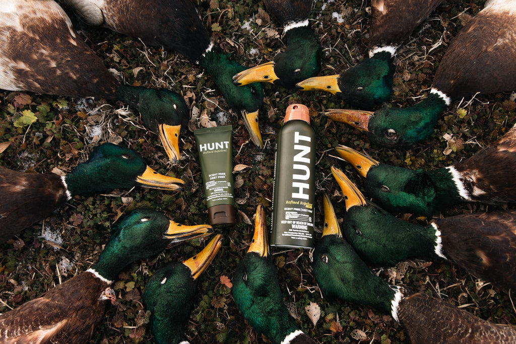 A photo of hunted ducks on the ground in a circle with HUNT Refined Repellent Lotion and Spray in the middle.