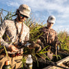 A photo of two hunters holding ducks.