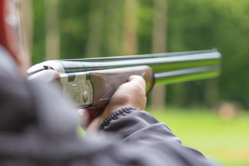 A picture of a hunter aiming a shotgun.